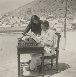 Ύδρα, αρχές της δεκαετίας του 1960. Η Τσάρμιαν Κλιφτ και ο Τζορτζ Τζόνστον στη γραφομηχανή του, στην ταράτσα του σπιτιού τους, με φόντο το νησί.